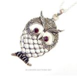 A silver owl shaped pendant necklace with ruby eyes and silver chain