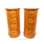 A pair of hardwood cylindrical bedside chests, each having four drawers
