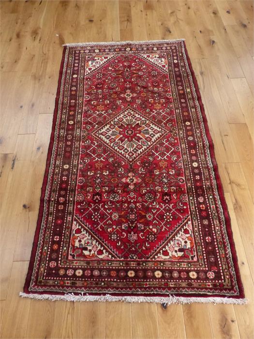 A northwest Persian rug, having an ivory lozenge on a red field with ivory spandrels