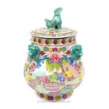A Chinese porcelain jar and cover, the finial in the form of a dog, with four mask handles