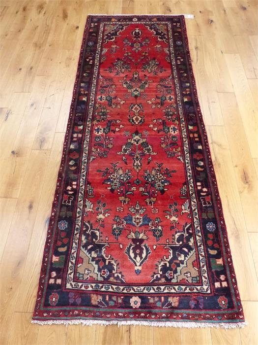 A northwest Persian runner, having floral designs on a red field, with spandrels to the corners,