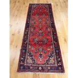 A northwest Persian runner, having floral designs on a red field, with spandrels to the corners,