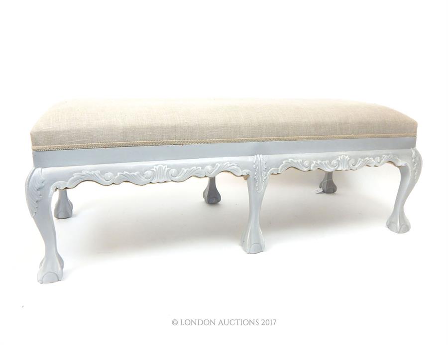 A hall seat, upholstered in grey linen, raised on a grey painted and distressed carved wooden frame