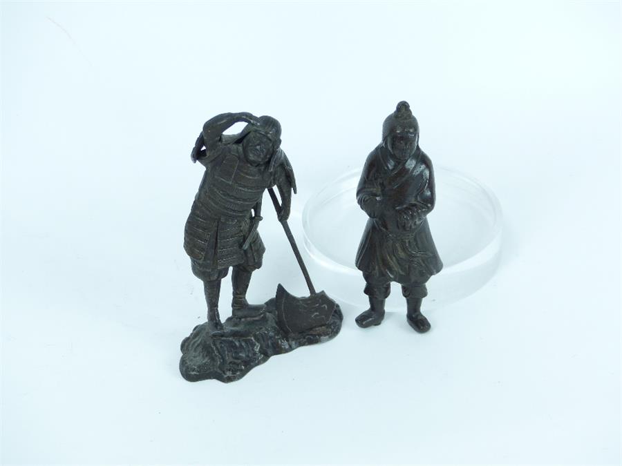 A Japanese bronzed spelter figure of a samurai warrior holding an axe and staring into the distance,