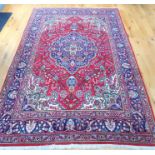 A large Persian Tabriz carpet with a medallion on a red field with spandrels, surrounded by one