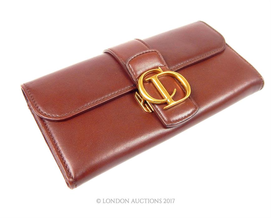 A Ladies Christian Dior purse; in brown leather with gold metal fitting