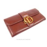 A Ladies Christian Dior purse; in brown leather with gold metal fitting