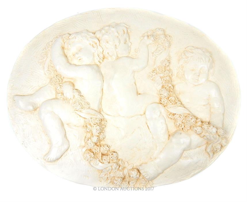 A contemporary, oval, plaster plaque depicting three Puttis with garlands of roses