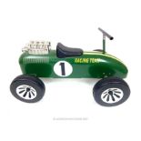 A vintage style child's ride-on car, in the style of a classic British racing car in racing green,