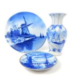 Three Delft blue and white items, including two plates decorated with a windmill, and a vase