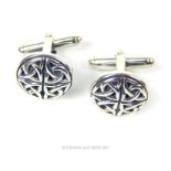 A pair of silver cufflinks featuring a Celtic knot design.