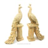 A pair of ceramic distressed finished peacocks, modelled on classical style plinths