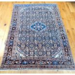 An antique Malayer rug with a small midnight blue medallion on muted red field