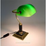 A brass banker's lamp with a green glass adjustable shade, raised on a green marble cylindrical stem