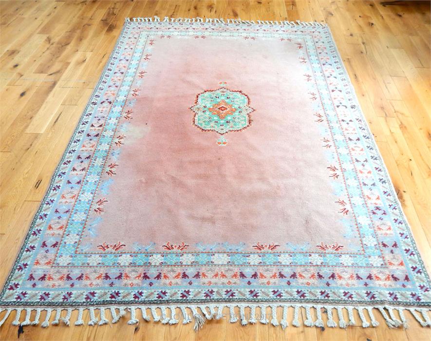 A Moroccan carpet, the green medallion on a pink field