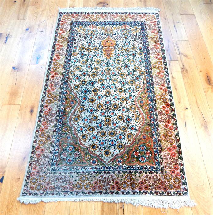 An pure silk Qum rug, with floral designs on an ivory field