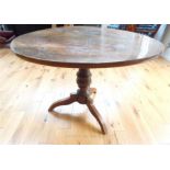 A 19th century walnut circular centre table with tilt top raised upon baluster support and tripod