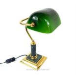 A brass banker's lamp with a green glass adjustable shade, raised on a green marble cylindrical stem