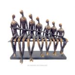 A bronzed resin sculpture after Giacometti depicting seven graduated figures,