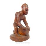 A carved wooden tribal figurine of a wood carver; 25cm high.