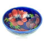 A Moorcroft pottery bowl, decorated with flowers on a blue ground