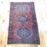 An antique Kazak rug, having three medallions on a red field