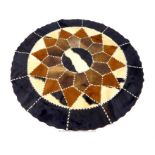 A circular rug formed of sections of cow hide sewn together