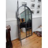 A distressed metal architectural style arched wall mirror