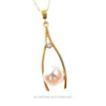 A charming, yellow gold diamond and pearl wishbone pendant on an 18 ct yellow gold chain
