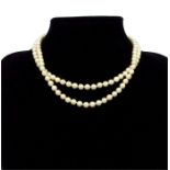 A cased, strand of cultured pearls with a large, 18 ct yellow gold, diamond and sapphire