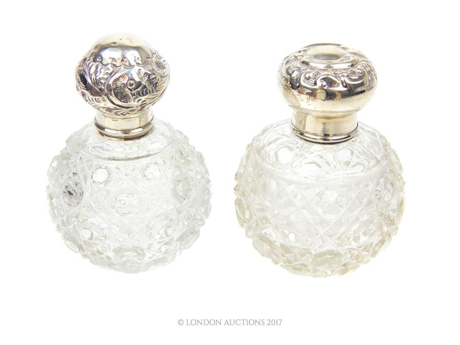 Two Edwardian cut glass perfume bottles with sterling silver lids and collars