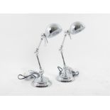 A pair of chromed, articulated desk lamps