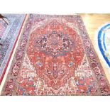 A Persian Heriz carpet, decorated with a star medallion on a red field with spandrels, one Frieze