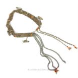 A Bedouin white metal belt adorned with charms, beads and inset with amber glass.