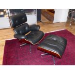 A designer black leather and plywood chair with stool