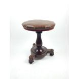 A Victorian circular upholstered swivel topped stool with carved based.