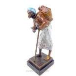 A painted bronzed metal figurine of an Asian gentleman carrying water; indistinctly signed base;