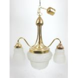 A brass chandelier with three branches and four ornate frosted glass shades