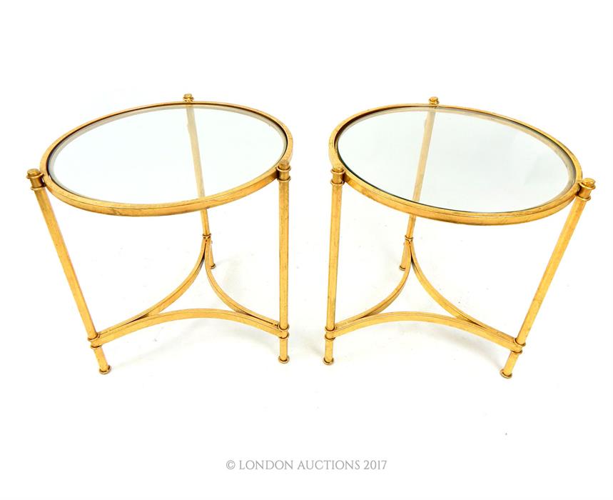 A pair of gilt metal circular occasional low tables with plate glass tops