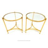 A pair of gilt metal circular occasional low tables with plate glass tops