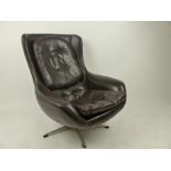 A 1970's Danish brown leather chair, raised on swivel supports