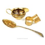 Four silver gilt items: jug, spoon and two napkin rings; 243g