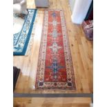 A fine Kazak runner rug with five medallions upon a red ground; 330cm x 90cm.