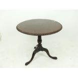A mahogany circular tilt-top table with pie-crust edge.