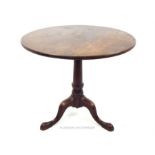 An antique, oak, circular, occasional table on three out-swept legs