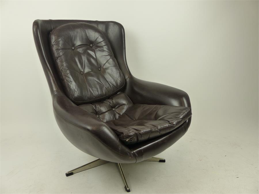 A 1970's Danish brown leather chair, raised on swivel supports