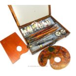A vintage mid 20th century wooden paint box with oil paints, brushes and two palette knives along