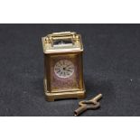 A decorative miniature brass carriage clock with painted porcelain panels.