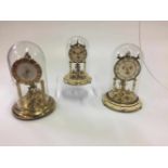 Drie klokken onder stolp. Three clocks under glass bell.