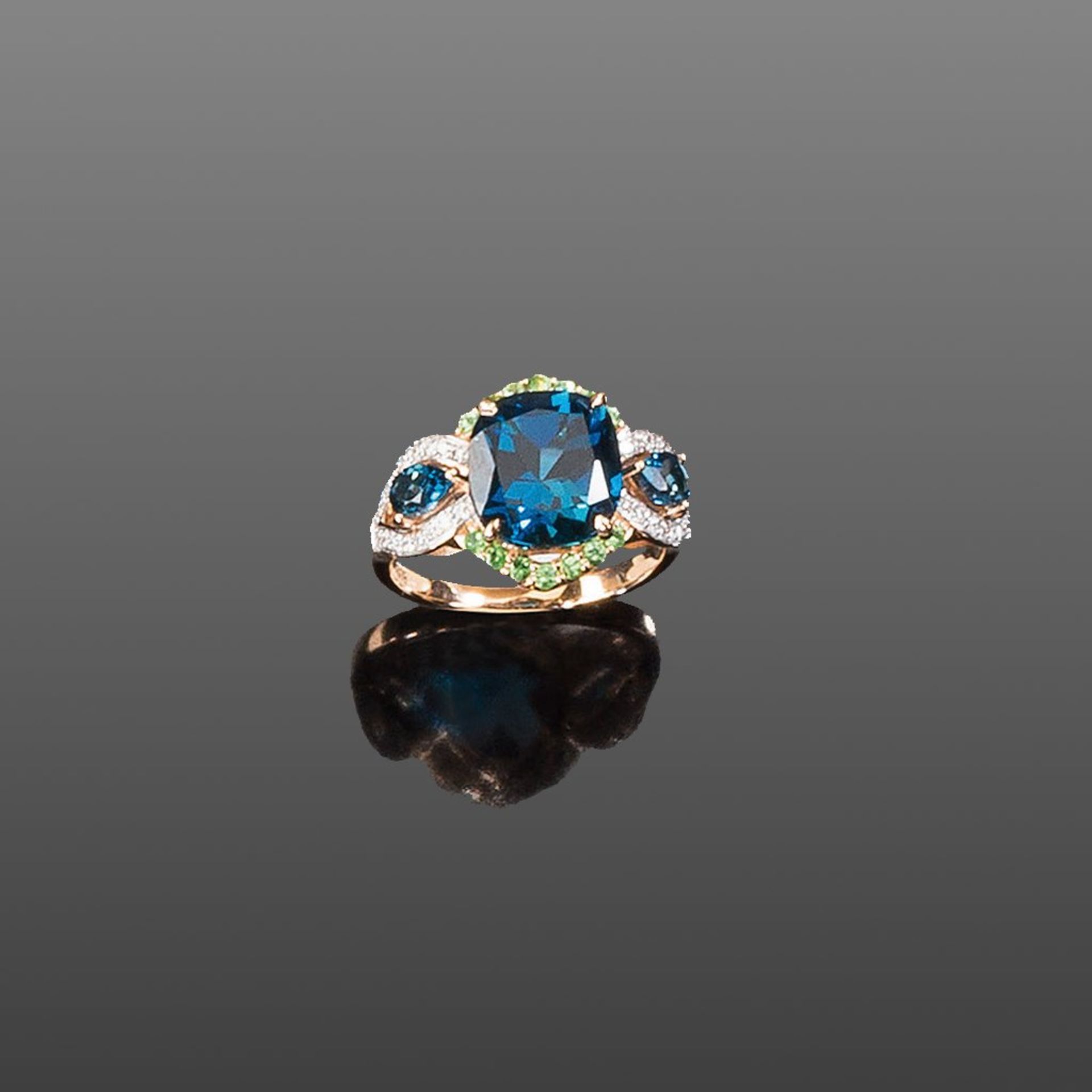 Blautopasring. Blautopas London blue, ca. 5,50 ct. Kleine Tsavorite. Brillanten ca. 0,20 ct. Fassung